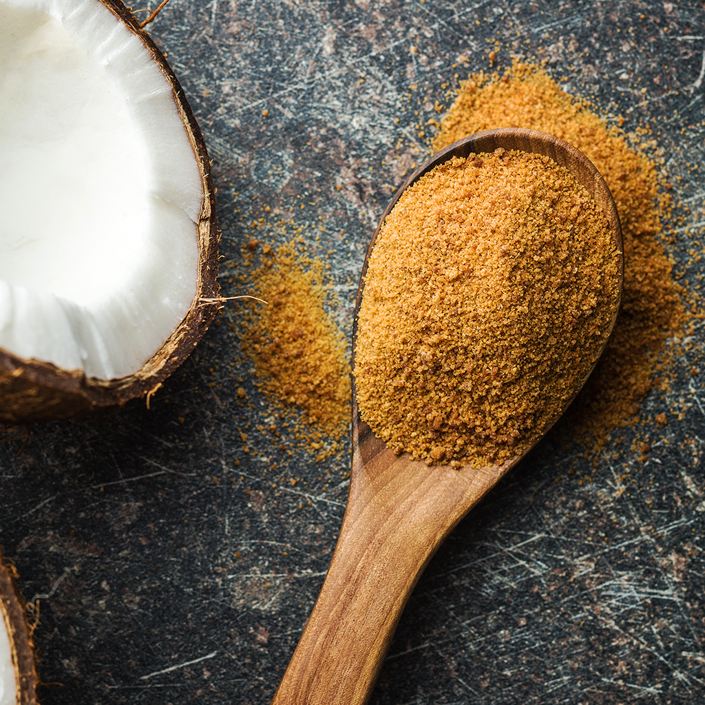 Imagem com uma colher cheia de açucar de coco e uma imagem de um coco